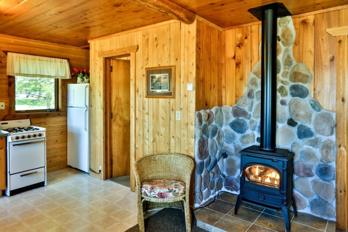Sunset Cabin kitchen, gas fireplace, rattan chair.