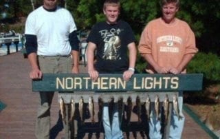Two men and young man posing with several caught fish.